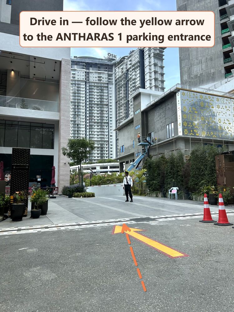 Driveway with a yellow arrow pointing to the Antharas 1 parking entrance