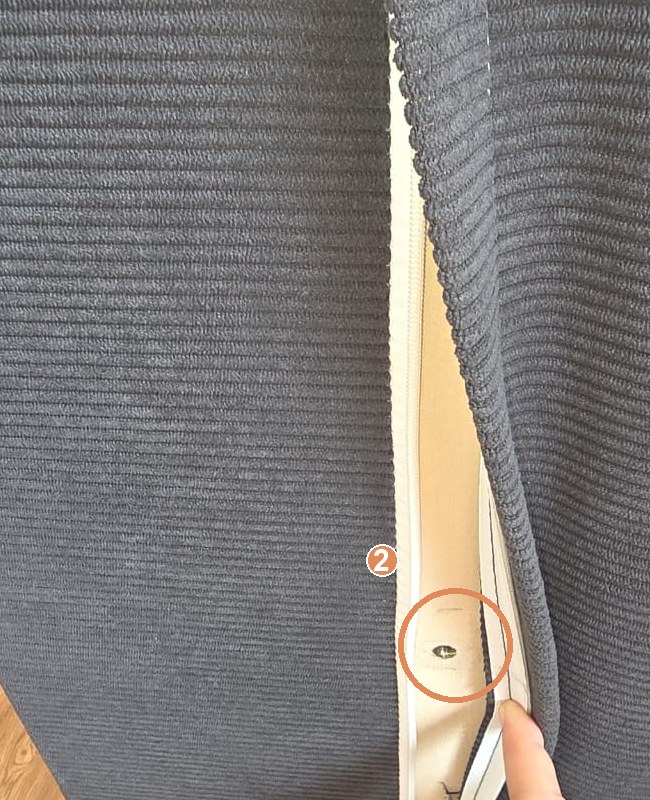 The zip-open flap on the sofa back revealing the screw socket, ringed and marked 2